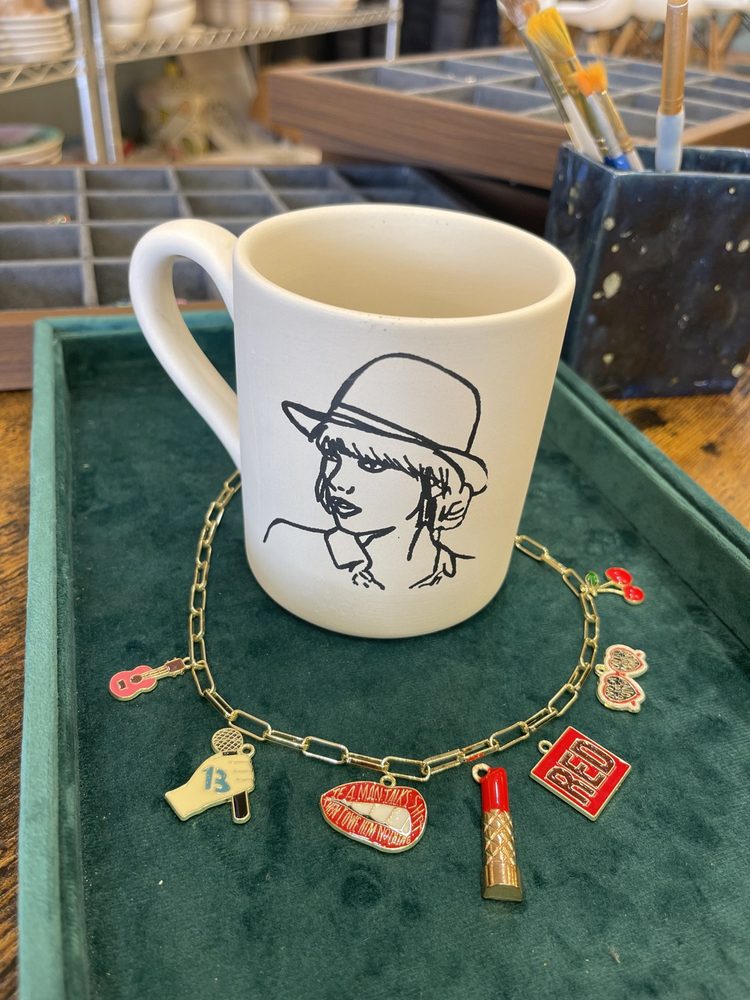 Charm bracelet next to a hand-painted mug